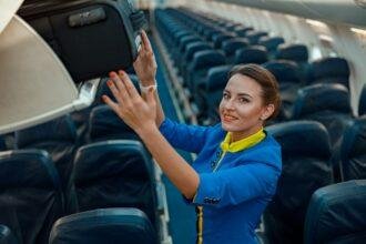 Stewardess putting travel bag in overhead luggage shelf in airplane