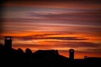 a red sky with some clouds and a clock tower